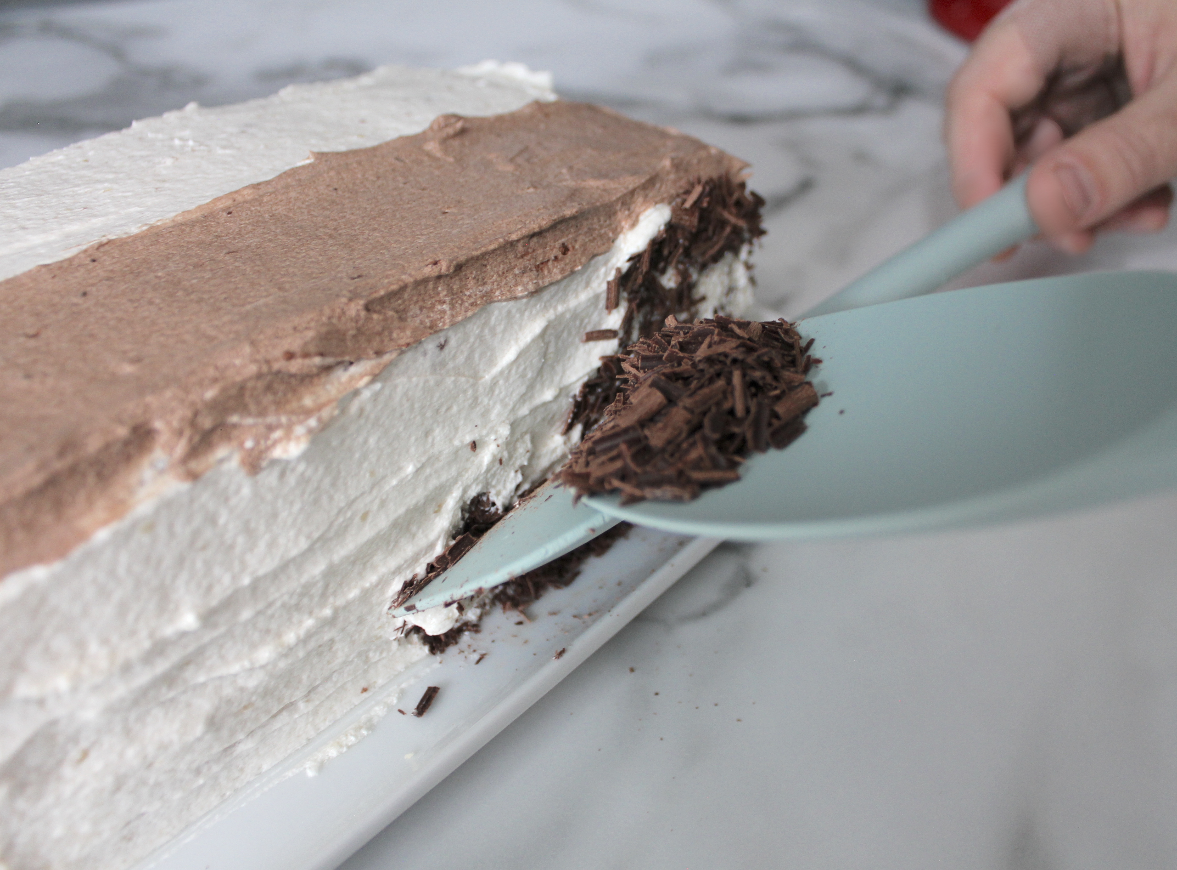 Using two spatulas to apply chocolate shavings.