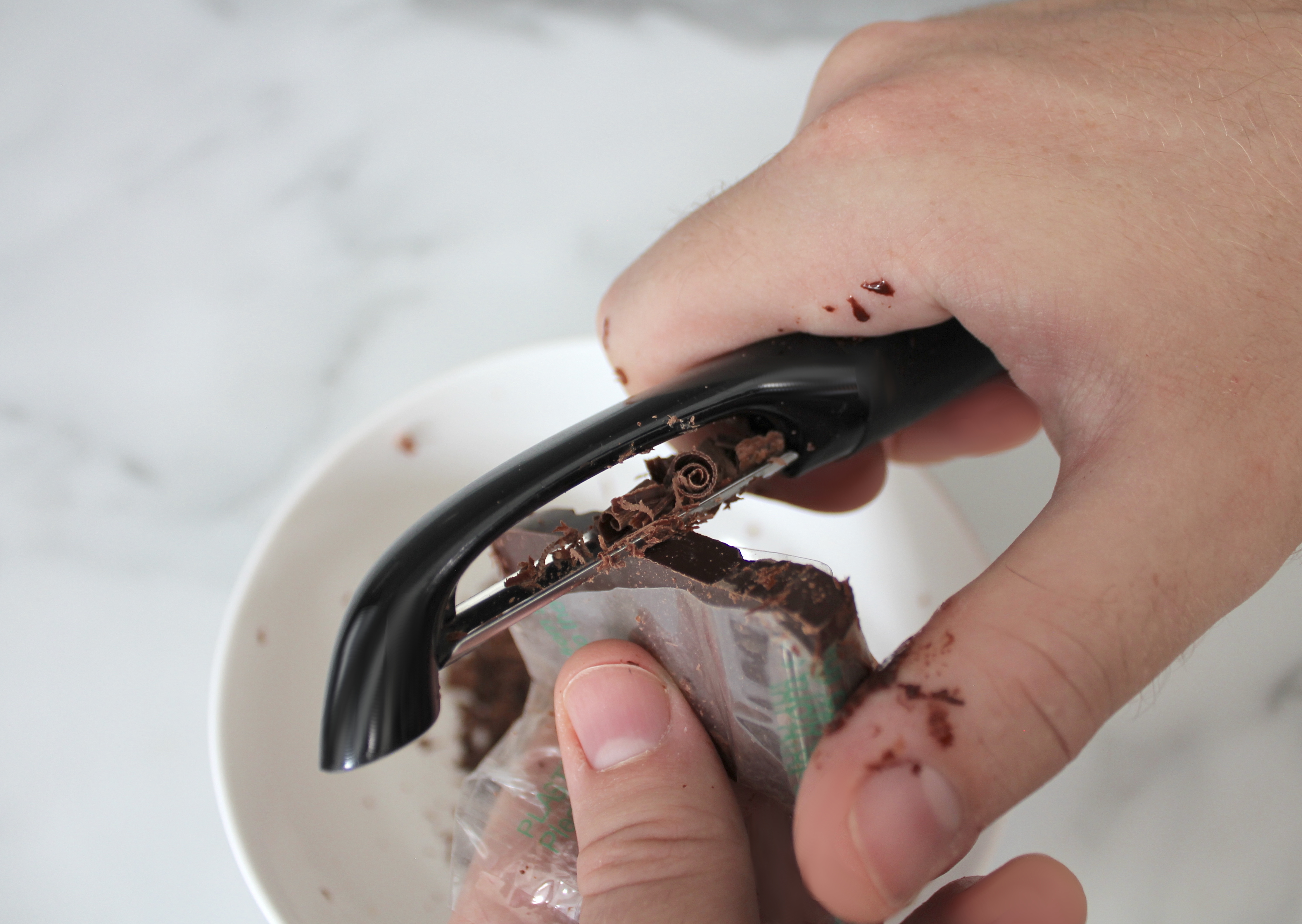 Preparing chocolate shavings with a peeler.